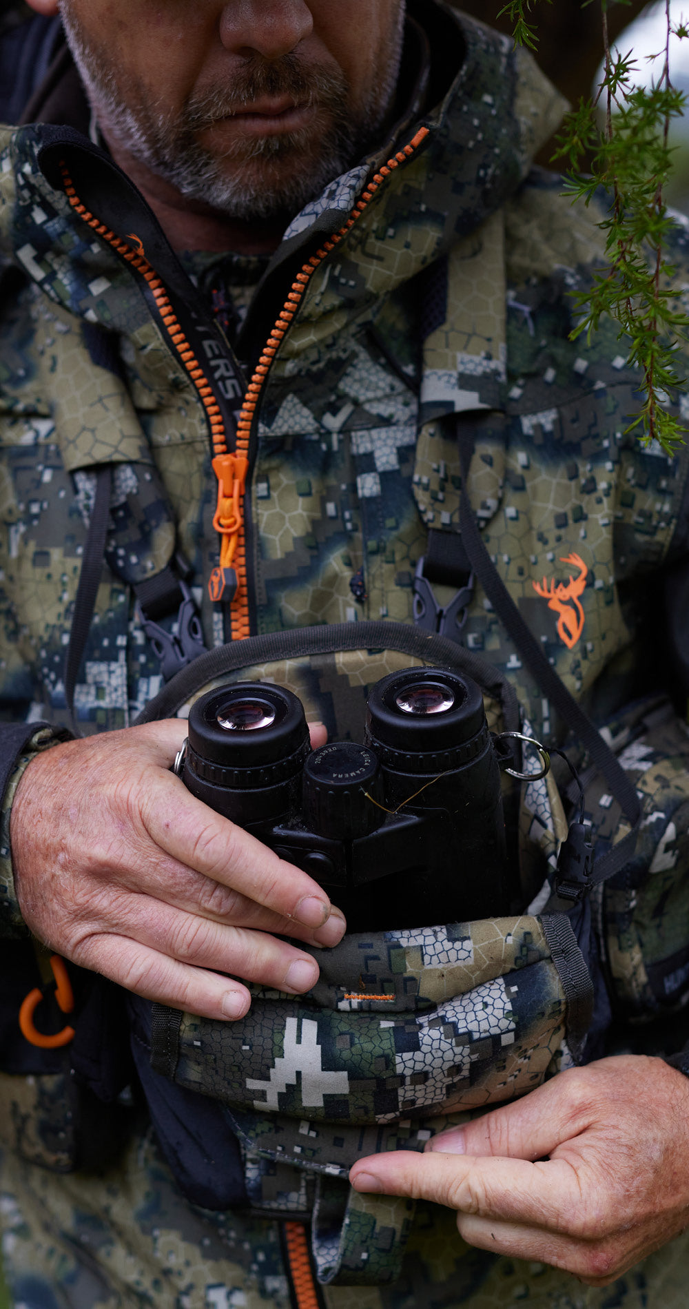 Person in camouflage clothing holding binoculars