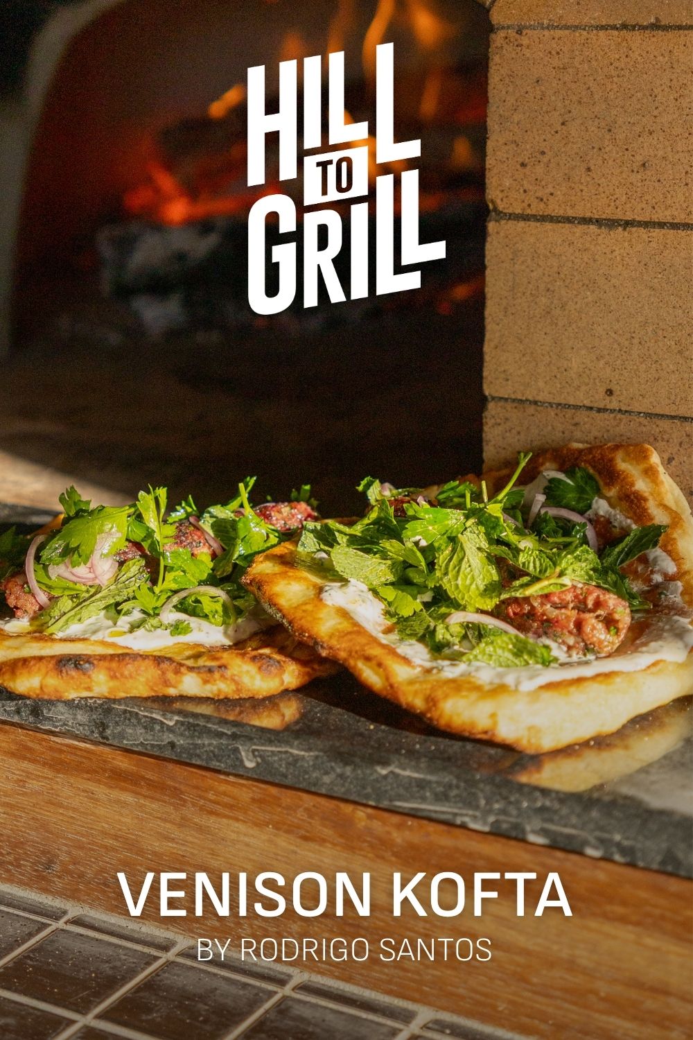 Two pizzas with green toppings on a stone surface, with 'Hill to Grill' branding in the background.